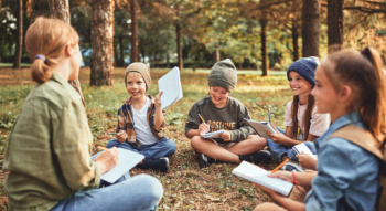 a teacher sitting int he grass with students