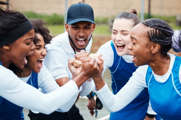 A women's sports team cheers with a coach