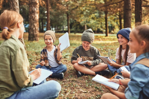 a school group sitting in the grass with a teacher