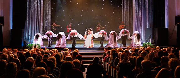 actors bow on a stage in front of a theater audience